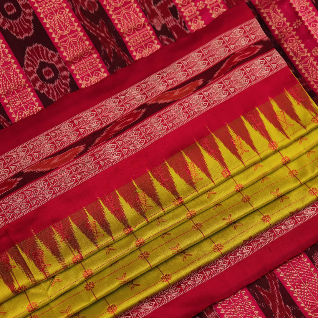 Close-up view of the soft silk fabric texture of a green and magenta Sambalpuri saree with intricate butta patterns