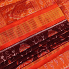 Close-up of maroon and orange Sambalpuri silk saree fabric texture, showcasing handloom weave and motif details.