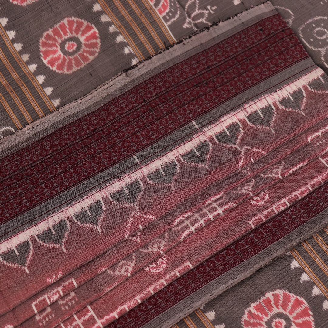 Close-up of a multicolored silk Sambalpuri saree fabric showing the intricate handloom texture and motifs.